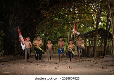 Concept photo of village children who are excited and play in the Indonesian independence edition carrying the flag. : Bantul, Indonesia - 15 August 2021