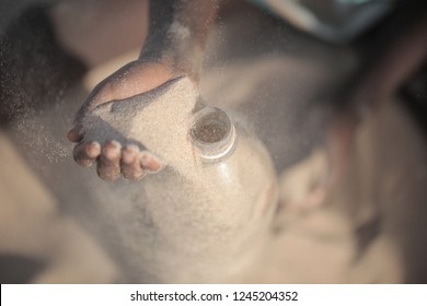 Concept Photography, Eco Building: Aerial Close Up  African Man Hand Filling Up With Sand A Plastic Water Bottle, Making Ecobrick, Outdoors On A Sunny Summer Day, In Gambia, Africa On Atlantic Beach