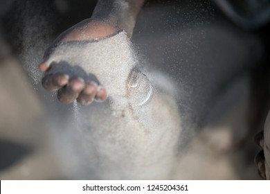 Concept Photography, Eco Building: Aerial Close Up  African Man Hand Filling Up With Sand A Plastic Water Bottle, Making Ecobrick, Outdoors On A Sunny Summer Day, In Gambia, Africa On Atlantic Beach