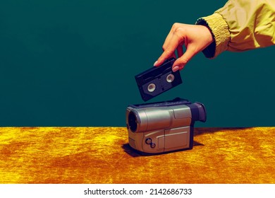 Concept Of Pop Art Photography. Using Retro Gadgets. Human Hand Holding Videocamera Isolated On Green-yellow Background. Vintage, Retro 80s, 70s. Complementary Colors. Concept Of Memory, Nostalgia