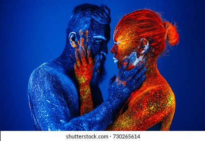 Concept. Portrait of a bearded man and woman painted in ultraviolet powder.