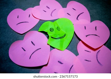Concept of positive attitude made with heart-shaped papers, where everyone is sad and one smiles despite being wrinkled and broken. - Shutterstock ID 2367157173