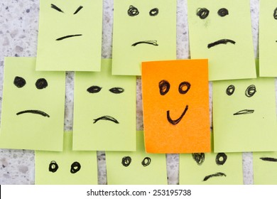 concept for a positive attitude with small office notes with multiple faces and one that stands out with a smile - Shutterstock ID 253195738