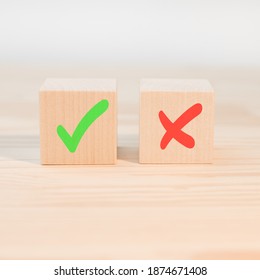 Concept of positive or negative decision making or choice of approval or rejection. Tick mark and cross mark x on wooden cubes. Wooden blocks with green check mark and red x.