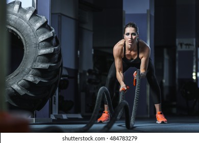 Concept: power, strength, healthy lifestyle, sport. Powerful attractive muscular woman trainer do battle workout with ropes at the gym