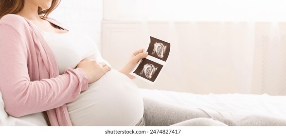 Concept of pregnancy and health care. Young mother waiting for baby, enjoying sonogram in bed, panorama with empty space - Powered by Shutterstock