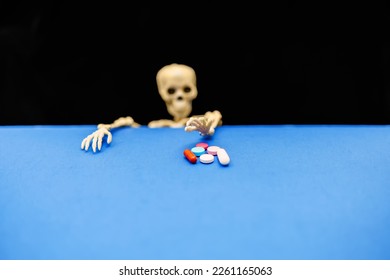 The concept of the problem of drug addiction. The skeleton reaches with his hand to various pills