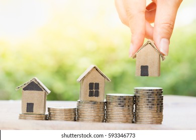 Concept for property ladder, mortgage and real estate investment. Woman's hand putting house model on top of coins stack. - Shutterstock ID 593346773
