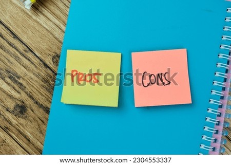 Concept of Pros or Cons write on sticky notes isolated on Wooden Table.
