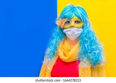 Concept of protection against coronavirus at carnival venice. A bright woman in a blue wig and yellow carnival mask, wearing a medical health mask from Virus crown celebrating the holiday. Copy space