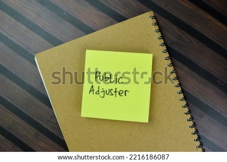 Concept of Public Adjuster write on sticky notes isolated on Wooden Table. Selective focus on public adjuster text