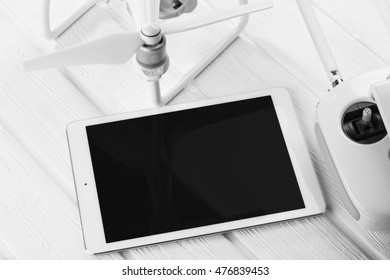 concept quadrocopter, tablet and remote control on a white wooden background