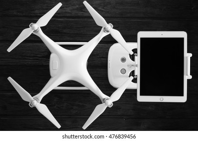 concept quadrocopter, tablet and remote control on a black wooden background