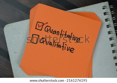 Concept of Quantitative or Qualitative write on a sticky notes isolated on Wooden Table.