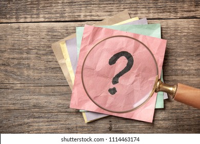 Concept with question mark on sticky note and magnifying glass