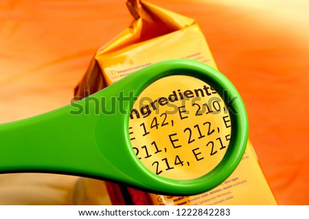 Concept of reading ingredients list on food package with magnifying glass. Magnifying glass on food additives label. 
