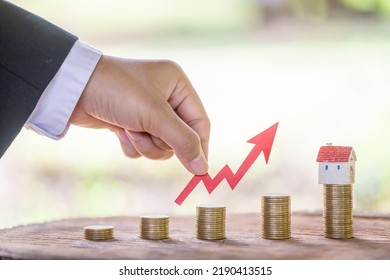 Concept of real estate investment.Business growth.House on a pile of coins.Stack of coins arranged in ascending order.The investor's hand catches the red arrow.Business investment ideas. - Shutterstock ID 2190413515