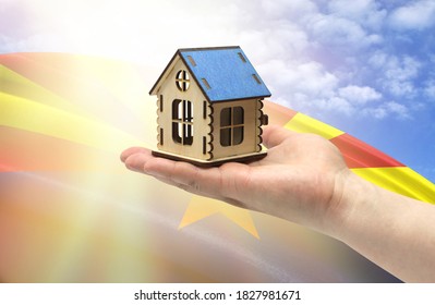 The concept of real estate mortgages, citizenship and accommodation. In hands holding a model of a wooden house against the background of the flag of State of Arizona.