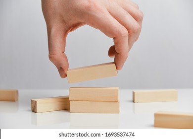 Concept of rebuilding a business after bankruptcy. Hand holds wooden blocks on a white background. Close up.