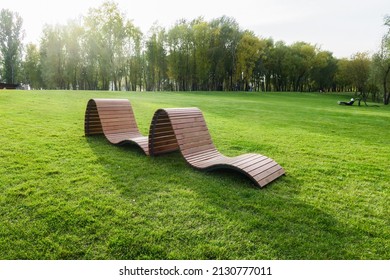 The Concept Of Recreation In A City Park. Sun Loungers And Benches On The Lawn With A Neatly Trimmed Lawn Without People. Panorama Of A Well-groomed Lawn With Beautiful Stripes After Mowing.