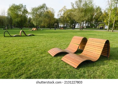 The Concept Of Recreation In A City Park. Sun Loungers And Benches On The Lawn With A Neatly Trimmed Lawn Without People. Panorama Of A Well-groomed Lawn With Beautiful Stripes After Mowing.