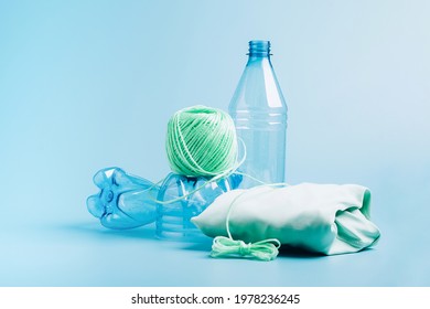 The concept recycling plastic. Empty plastic bottle and recycled polyester fiber, synthetic fabric blue background