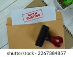Concept of Red Handle Rubber Stamper and Myth Busting text above Brown envelope isolated on on Wooden Table.