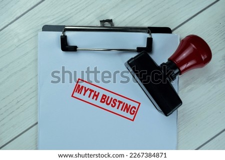 Concept of Red Handle Rubber Stamper and Myth Busting text isolated on on Wooden Table.