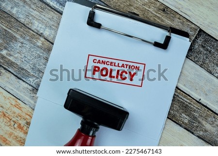 Concept of Red Handle Rubber Stamper and Cancellation Policy text isolated on on Wooden Table.
