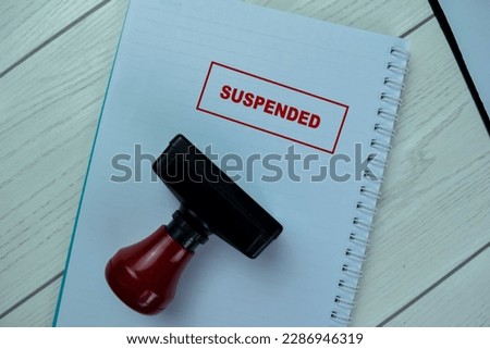 Concept of Red Handle Rubber Stamper and Suspended text isolated on on Wooden Table.