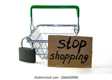 the concept of refusing to buy reasonable consumption is a shopping basket with a padlock and a sign saying stop shopping on a white background. High quality photo