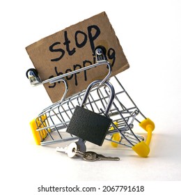 the concept of refusing to buy reasonable consumption is an inverted shopping cart with a padlock and a sign with the inscription stop shopping on a white background