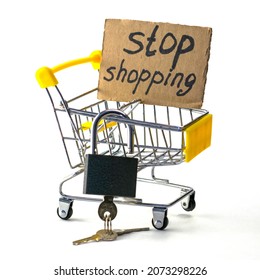 the concept of refusing to buy a reasonable consumption shopping cart with a padlock and a sign saying stop shopping on a white background. High quality photo