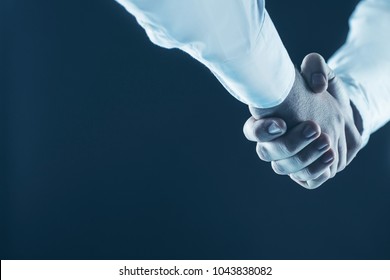 concept of a reliable partnership: a close-up of handshake of business partners on a black background. - Shutterstock ID 1043838082