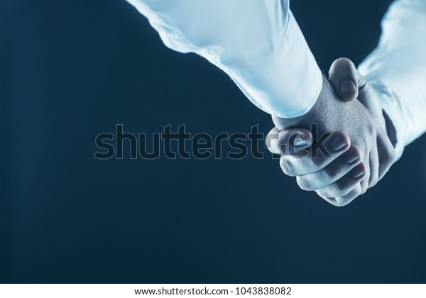 concept of a reliable\
partnership: a close-up of handshake of business partners on a\
black background.