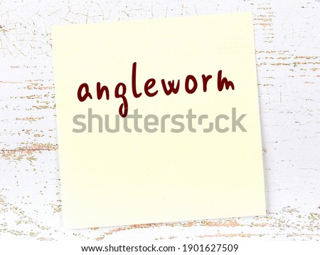 Concept of reminder about angleworm. Yellow sticky sheet of paper on wooden wall with inscription