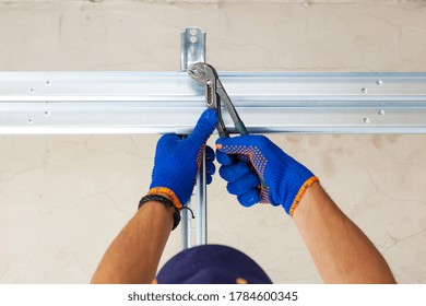 Concept Of Replacement Details. Cropped View Of Professional Worker Using Hand Tool And Install Metal Rail On Garage Door System In New House Under Construction