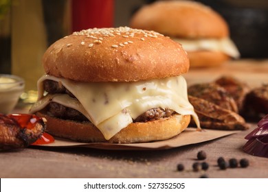 Concept: Restaurant Menus, Healthy Eating, Homemade, Gourmands, Gluttony. Classic Double Cheeseburger With Ingredients, Drinks And Potato Wedges On Messy Vintage Wooden Background.