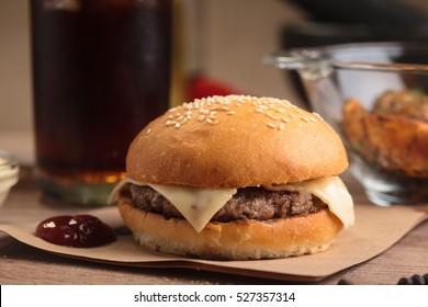 Concept: Restaurant Menus, Healthy Eating, Homemade, Gourmands, Gluttony. Classic Cheeseburger With Ingredients, Drinks And Potato Wedges On Messy Vintage Wooden Background.