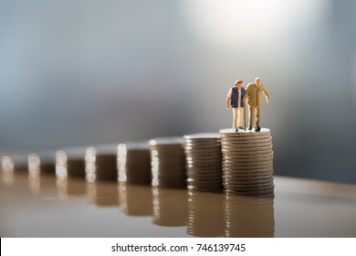 Concept of retirement planning. Miniature people: Old couple figure standing on top of coin stack. - Shutterstock ID 746139745