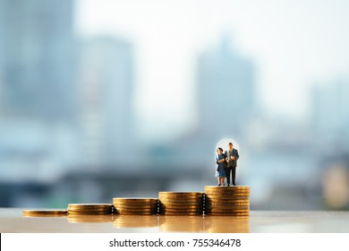 Concept of retirement planning. Miniature people: Old couple figure standing on top of coin stack.