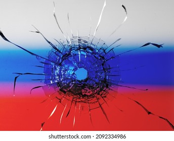 The concept of Russian aggression. Bullet hole on the background of the defocused Russian flag.