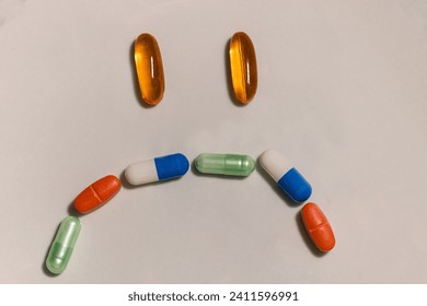 Concept of sad face in ironic shape formed of pills and vitamins.