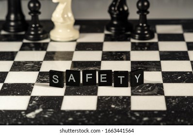 The concept of Safety represented by black and white letter tiles on a marble chessboard with chess pieces