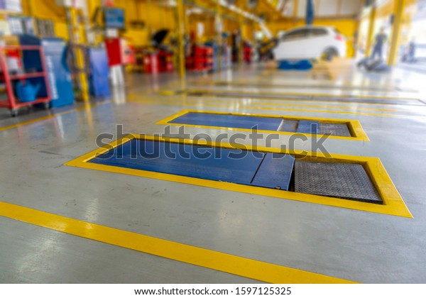 The concept of safety\
zones in automobile repair and inspection services\
.Inside the car\
service center with epoxy floor and the electric lift for\
background .