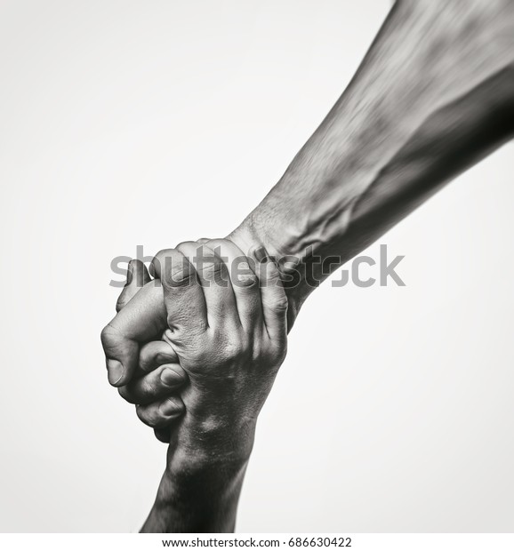 Concept of salvation. Black\
and white image of the hands of two people at the time of rescue\
(help).