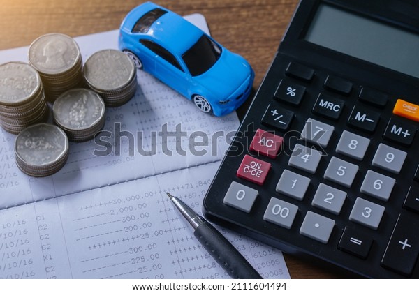 The concept of saving money. Saving money to buy a\
car and repairs.Miniature car model,calculatorand Financial\
statement with coins.