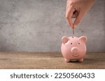 The concept of saving money for friends for future use, a woman is putting coins into a pink piggy bank, saving for friends for further education, business and sickness.