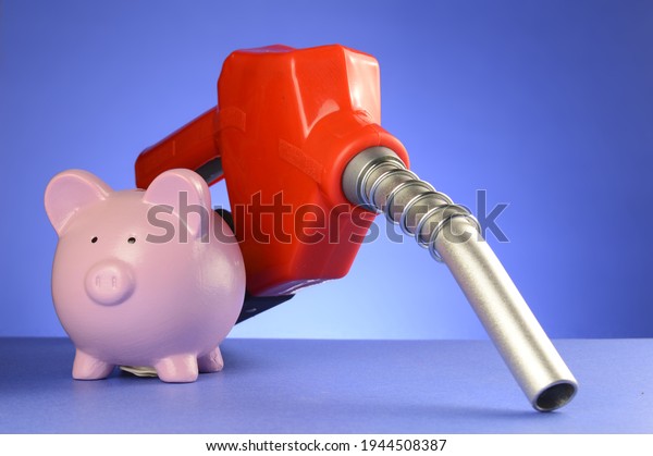 A concept of saving\
money at the gas pumps using a piggy bank and red fuel pump over a\
blue background.