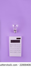 The concept of savings electricity. Reducing the payment of utility bills. A incandescent lamp, calculator on a purple background. Flat lay, top view
					